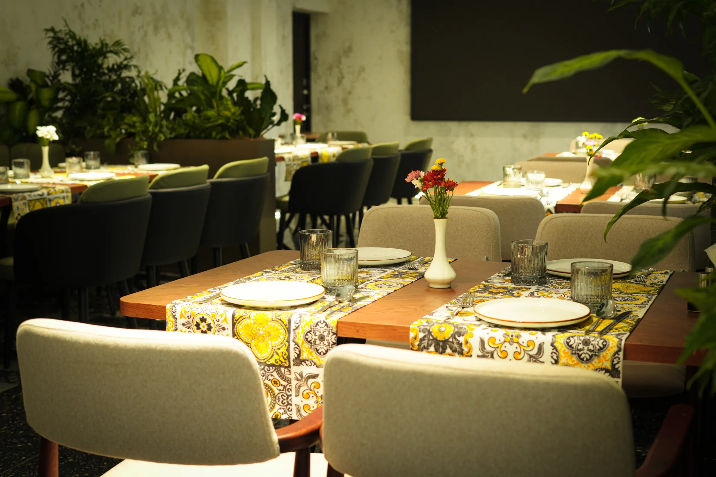 The Salute dining room: tables with patterned runners, flowers in vases and live plants